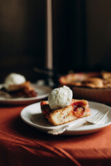slice of plum cake with a scoop of ice cream on top. portion of pie on a white plate with a fork close-up.