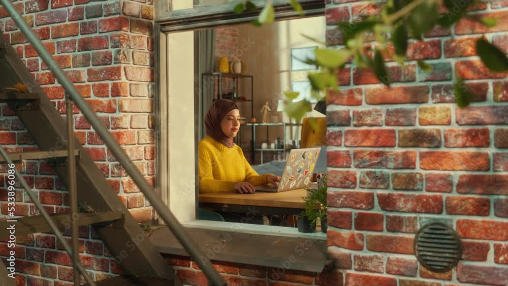 Poster smiling arab woman using laptop computer in her apartment on a warm sunny day. remote work concept w