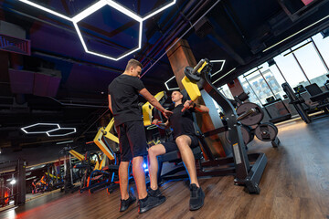 Fototapeta na wymiar Male working out with trainer. Sportive healthy in sportswear.