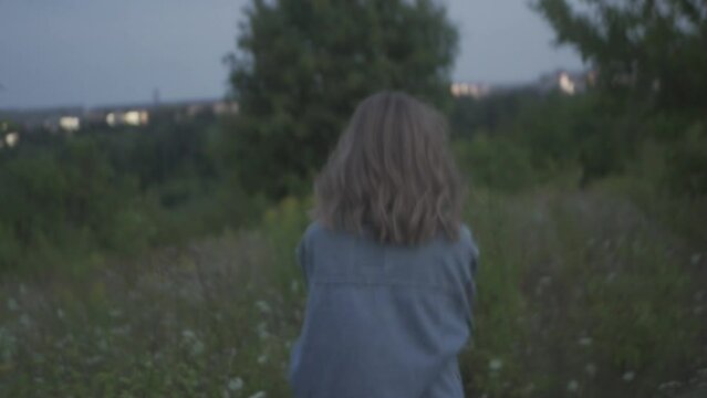 Soft focus, noisy footage of a girl running away at night field with trees. Scary and dangerous things outdoors. Horror film concept. Maniac stalks a victim. First view.