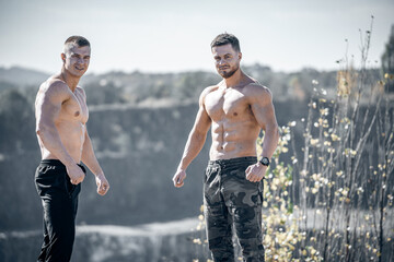 Strong fit men motivated workout. Outdoor training on rocky background.