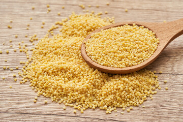 pile of sorghum or sorghum grain, millet grain or millet seed in wood spoon on wooden table background                                                   