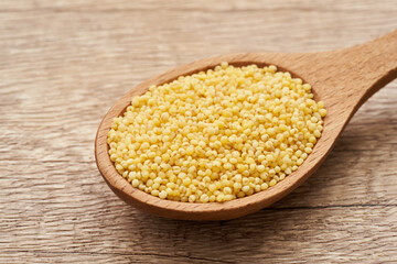 pile of sorghum or sorghum grain, millet grain or millet seed in wood spoon on wooden table background                                                   