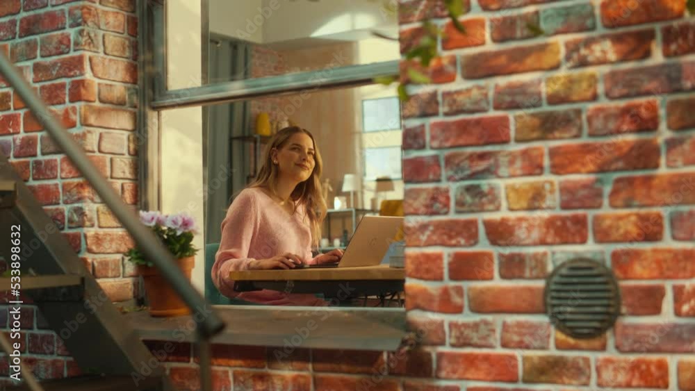 Aufkleber young attractive female in pink sweater working on a laptop computer while sitting behind a table in
