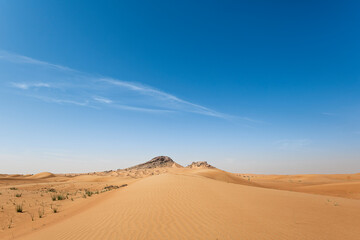 Sand Dunes landscape with Mountains in the background and with blue sky with large copy space