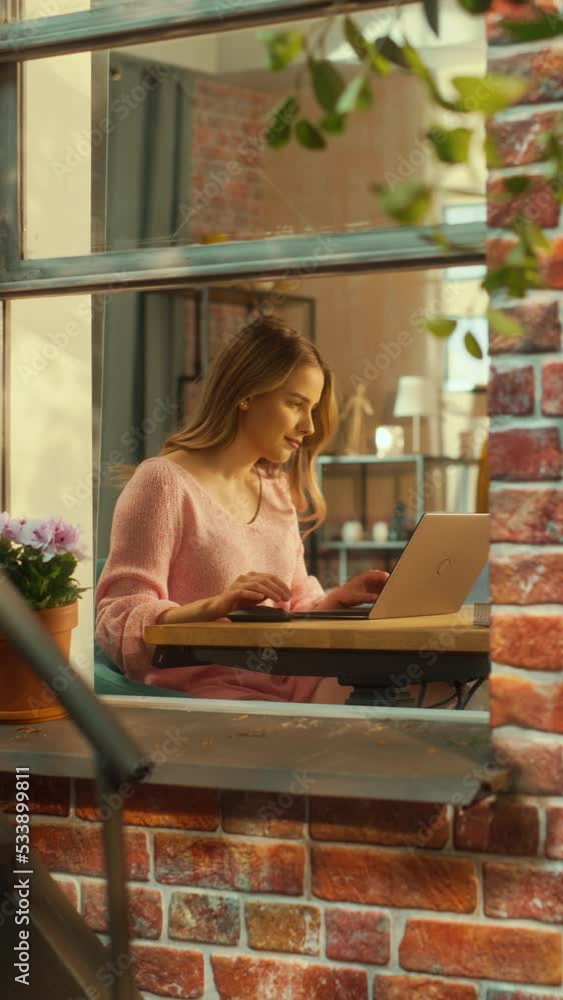 Poster vertical screen: portrait of a young female using laptop computer while sitting behind a table in he