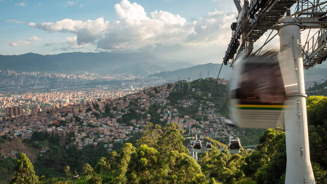 Modern public transit system in Medellin, Colombia, cable cars traveling over the city at sunset. 