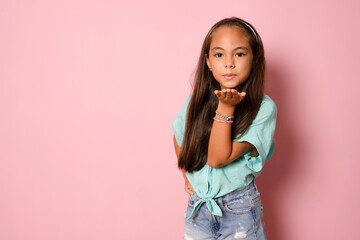 lovely brunette kid girl send a kiss at camera, love everyone, expresses emotions, isolated pink background