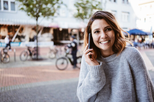 Young smiling woman talking on cell phone downtown