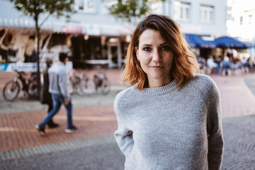 Young woman standing downtown and looking intensely into camera