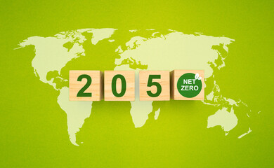Wooden cubes with text 2050 and net-zero icons over the world map on a green background