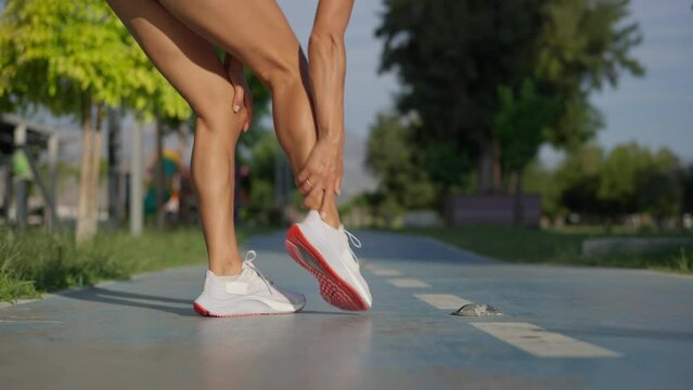 Young sportswoman having pain or injury during exercise and jogging on running track