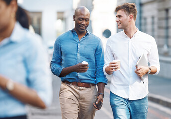 Men, walk and street with takeaway coffee while talk, smile and relax at lunch break. Black man, colleague and diversity in city at tea time, walking to office or workplace in discussion or talking