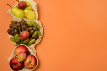 Reusable Grocery Bags With Fruits Reusable Packaging for Fruits and Vegetables Zero Waste Concept Orange Background Top View Copy Space