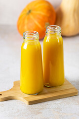Bottles of Juice for Healthy Diet Autumn Pumpkin Juice Wooden Tray Gray Background Vertical