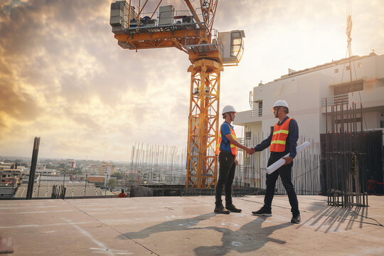 Architect and engineer construction workers shaking hands while working at outdoors construction site. Building construction collaboration concept . Selected focus