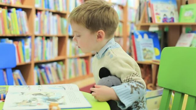 The kid in the library is looking at picture books. The child is drawn to knowledge. The concept of early development