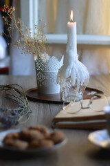 Cup of tea, plate with chocolate chip cookies, open book, reading glasses, lit candles and dry lavender flowers. Hygge at home, selective focus.