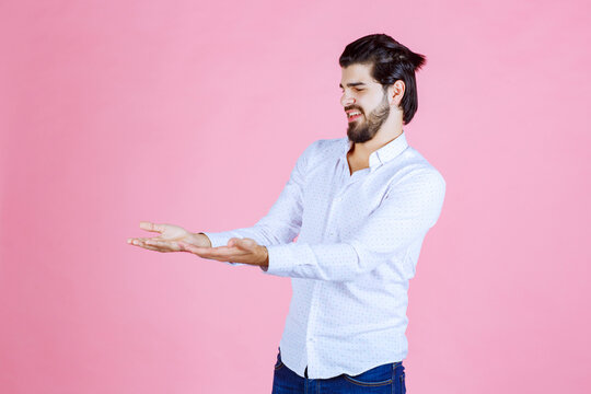 Man in a white shirt looks confused and trying to explain himself while using hand gests