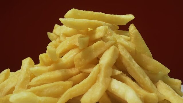 French fries on a red background rotates, appetizing potatoes with a slide camera. Fried potatoes on a turntable