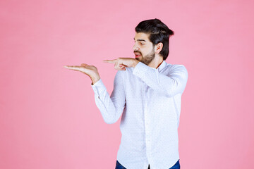 Young man with neatly styled hair in a white shirt making a gesture against a pink background