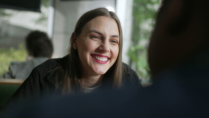 Young woman laughing and smiling at coffee shop closeup face portrait. Authentic female laugh and smile