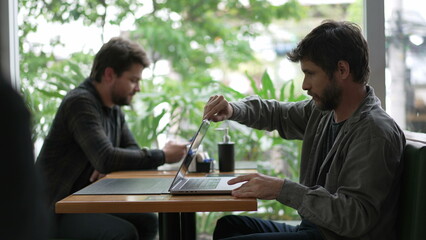 Young man opening laptop computer at coffee shop using modern technology remotely at cafe restaurant