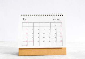 december 2023 Desktop calendar for planners and reminders on a wooden table on a white background.