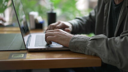 Young entrepreneur opening laptop and using modern technology inside seated at coffee shop table