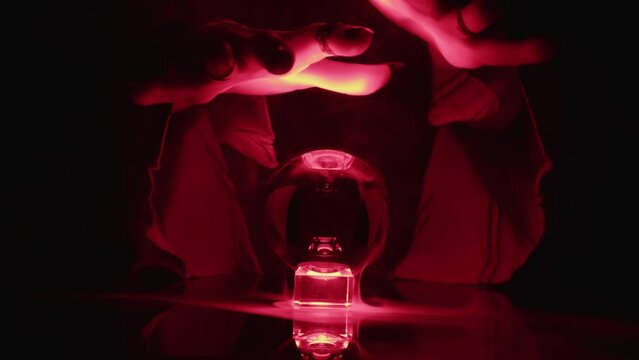 Energy of hands of esoteric magician interacting with crystal ball, magic ritual, bioenergetics.