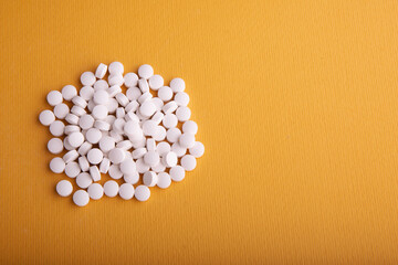 Fototapeta na wymiar White Pills On Orange Surface