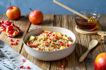 Sweet homemade barley porridge with pomegranate seeds, apples and honey. Rosh Hashanah celebration