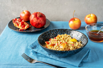 Sweet homemade barley porridge with pomegranate seeds, apples and honey. Rosh Hashanah celebration