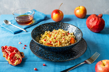 Sweet homemade barley porridge with pomegranate seeds, apples and honey. Rosh Hashanah celebration