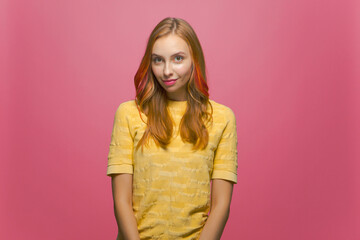 Caucasian young modern girl student with long dyed hair posing on pink studio background looking at...