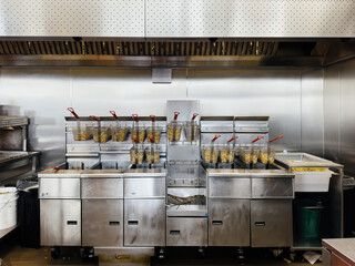 french fries cooking in multiple deep fryer mat machines inside fast food restaurant chain