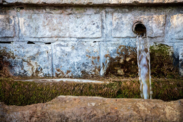 Old stone fountain with clear pure water running coming from a natural spring.