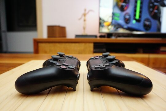 Closeup shot of two ps4 gamepads on wooden background