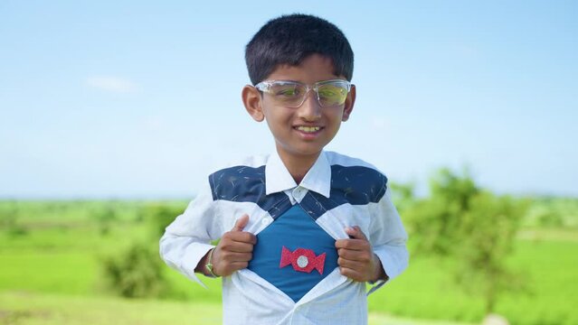 pan shot smiling teenager kid showing super power by removing shirt by looking at camera - concept of inspiration, strength and happiness