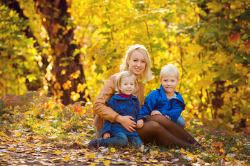 Fototapeta premium Mom and kids in autumn park, family fun. family enjoying a walk in nature. happy motherhood concept.