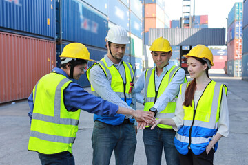 Group of multiethnic technician engineer and businessman in protective uniform with hardhat stand and stacking hands celebrate successful together or completed deal commitment at container cargo site