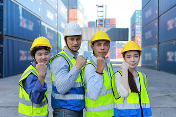 Group of multiethnic technician engineer and businessman in protective uniform with hardhat standing and raising hand celebrate successful together or completed deal commitment at container cargo site