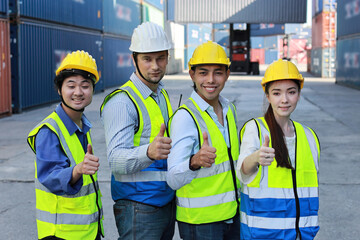 Group of multiethnic technician engineer or worker in protective uniform with hardhat standing and showing thumb up celebrate successful together or completed deal commitment at container cargo site