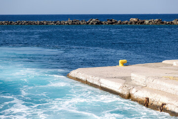 Greece, Naxos harbor destination Cyclades islands. View of corner of jetty and stone breakwater.