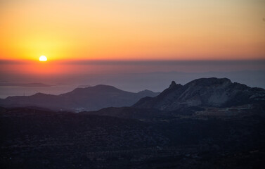 Sunset over Naxos island, Cyclades Greece. Sundown paints orange, gold yellow the sky background.