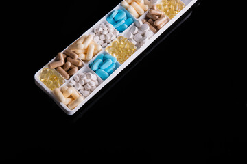 plastic container with pills on black background