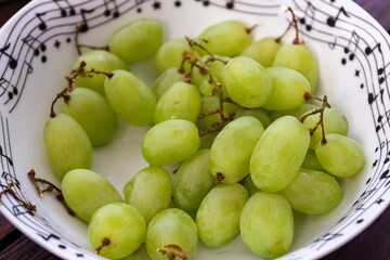 A close up portrait of a bowl of white or green grapes, ready to be consumed as a healthy snack. The fruit is full of vitamins and has a tasty sweet flavour.