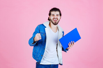 Man holding a blue folder and showing his fist