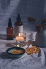 Vertical shot of essential oil bottles, dried lemon slices and a tea candle for a cozy autumn mood spa setting