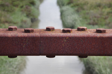 Rusty connecting steel parts of a road bridge structure over a canal